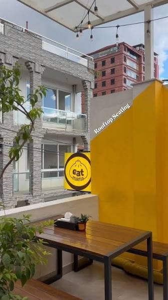 Rooftop seating with festoon lights and the eat momo sign